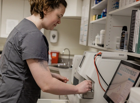 Veterinary technician operating an in-house diagnostic lab analyzer machine